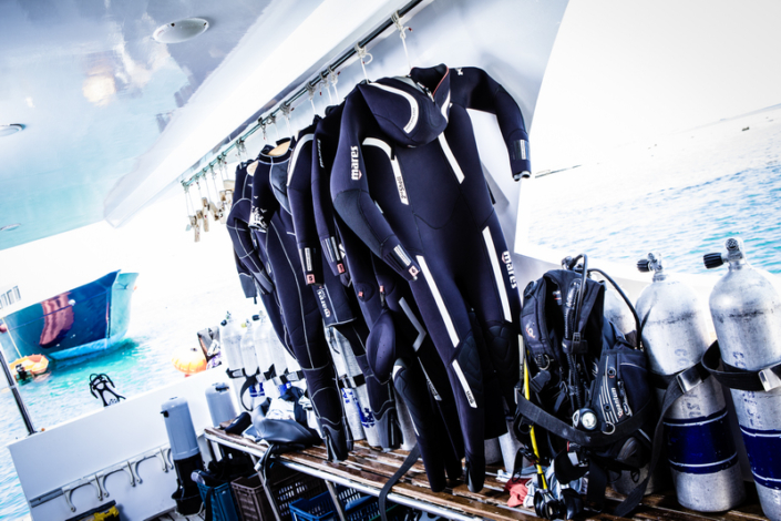 Mares wetsuits haning on the boat with tanks beside